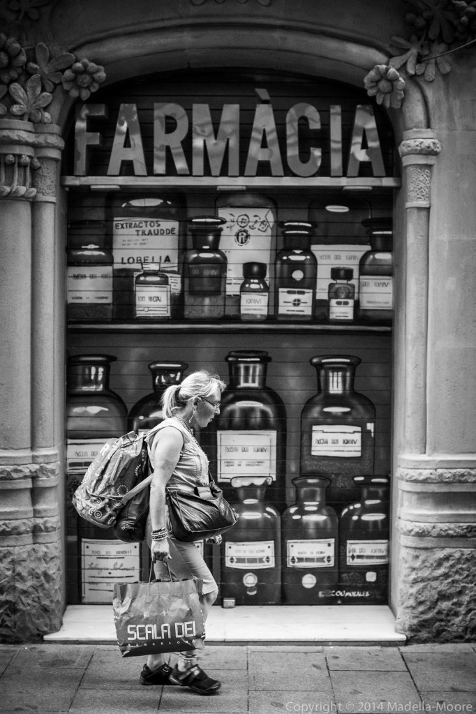 Heavily laden woman in front of pharmacy with painted bottles
