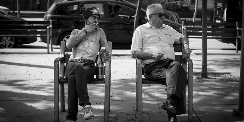 Two men sitting awkwardly on a Bench, Plaça de la Universitat, Barcelona.