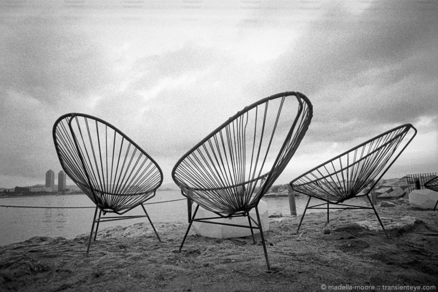Three string chairs, on the beachfront at Barceloneta.
