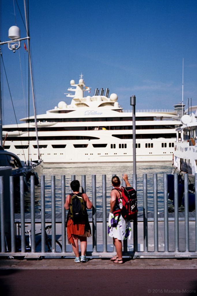 People looking at a luxury yacht behind a security fence, Barceloneta